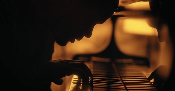 silhouette of a face leaning over a piano