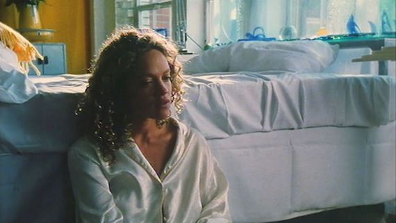a woman sitting on the floor next to a bed