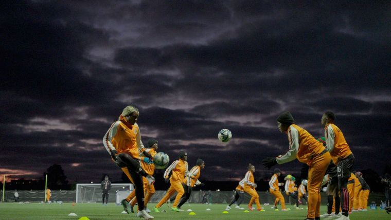 a womens soccer team practicing with a dark stormy sky in the background