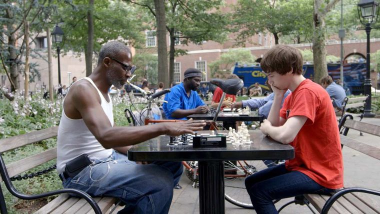Older Black man and younger white man playing chess