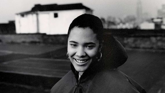 a woman with short hair and hoop earrings wearing a hooded jacket