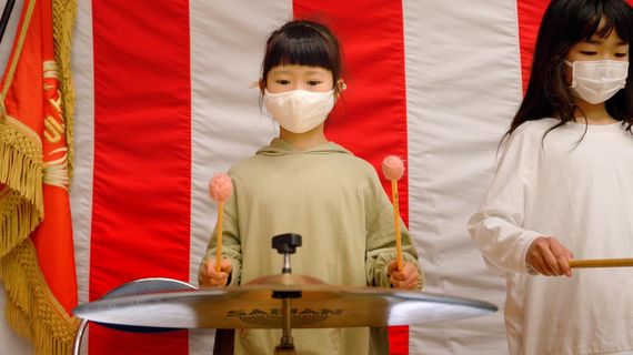 a young girl up on stage standing in front of a big drum