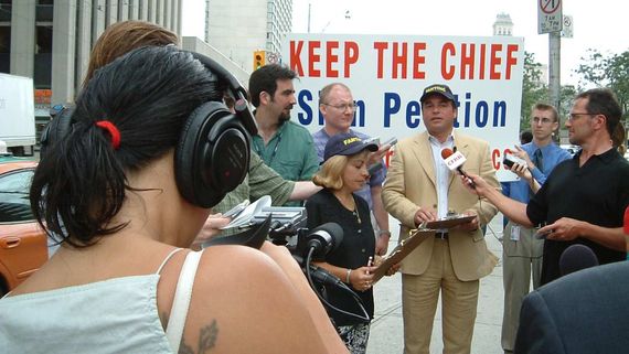 a man with a baseball cap being interviewed by reporters