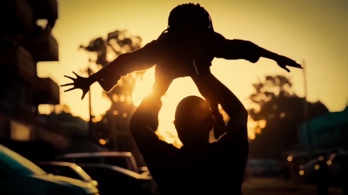 a silhouette of someone holding a kid up in the air