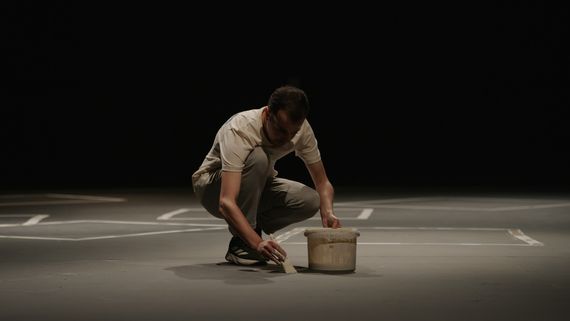 Man painting with chalk paint on black stage