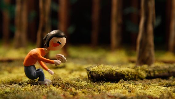 a clay model of a woman crouching in the forest to look at something