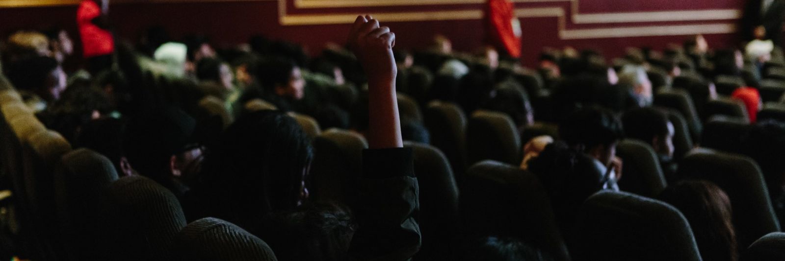 Student in theatre with hand raised