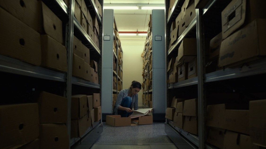 someone sitting on the floor between shelves