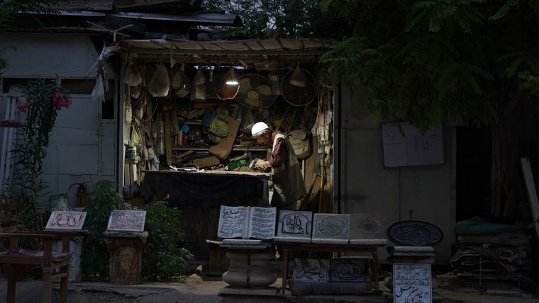 late evening,  a man working in a shop with a single light on