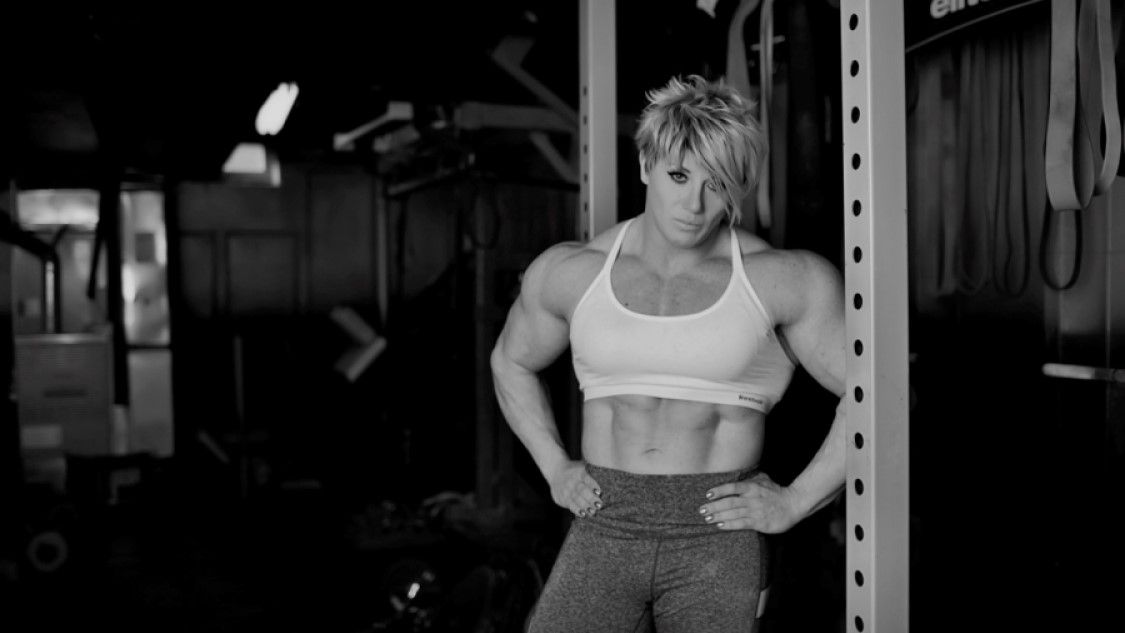 a fit woman standing in front of gym equipment
