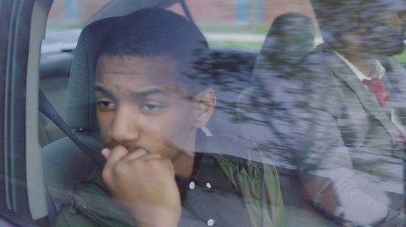 a young man looking out the passenger window of a car