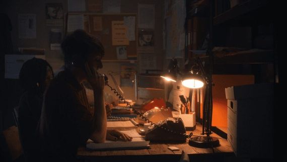 someone on the phone sitting at a dimly lit desk