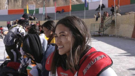 a woman smiling wearing hockey shoulder pads