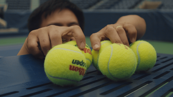 hands grabbing a bunch of tennis balls