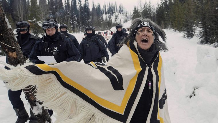 a Wet’suwet’en woman with several police officers passing behind her