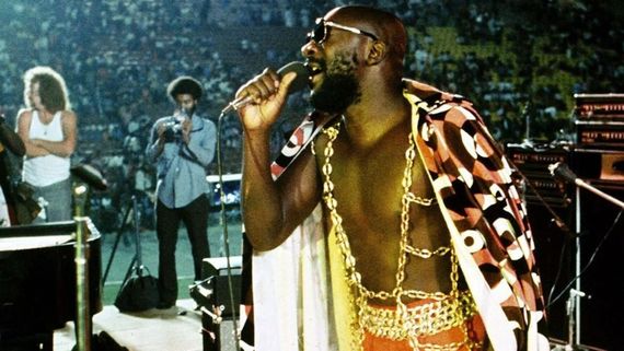 a man with sunglasses and gold chains singing on stage