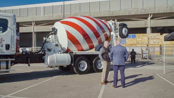 two men standing by a cement mixer