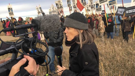 Woman reporter in front of protesters