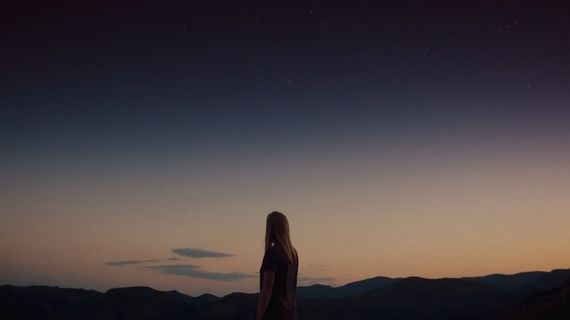 a silhouette standing on the horizon at dusk