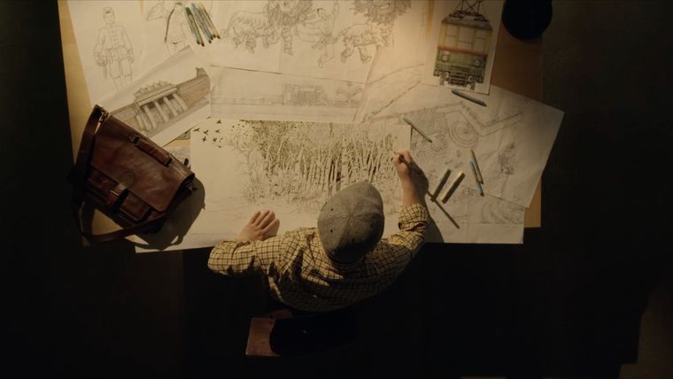 an ariel view of someone sitting at a large desk sketching