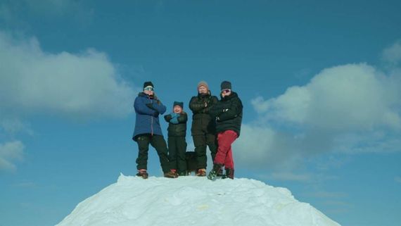 four people at the top of a snowy mountain